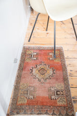 Distressed Oushak rug showing faded orange and dusty rose pile with grey geometric motifs.