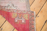 Distressed Oushak rug corner showing faded rose pile and hand knotted geometric back.