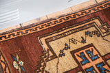 Vintage Oushak rug corner featuring geometric copper-tangerine border and aqua tribal motifs.