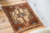 Fringed corner of a vintage Oushak mat, highlighting aqua blue and copper tribal arrow designs.