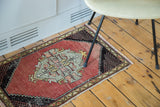 Distressed vintage Oushak rug showing cinnabar red field, checkered spandrel, and meandering border.