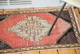Distressed cinnabar red field and black checkered spandrel on a vintage Oushak rug mat.
