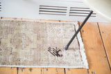 Distressed Oushak rug mat texture with subtle mauve hues, decorative bare spots, and fringed edge.