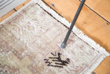 Decorative texture of distressed Oushak rug, highlighting worn pile, fringe, and faded motifs.