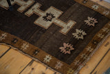 Turkish Oushak rug's bronze repeating star border, chocolate field, and hand-knotted fringe.