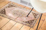 Distressed Turkish Oushak rug mat with a soft mauve field and scrolling floral border.