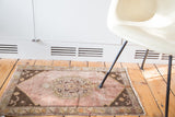 Distressed Oushak rug lower left corner, fringed with a dark brown stepped spandrel and floral border.