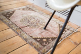 Distressed Oushak rug mat corner with soft mauve field, stepped spandrel, and floral border.