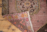 Vintage distressed Oushak rug corner, showing fringe, woven reverse, and faded mauve field.
