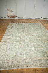 Distressed Oushak carpet border showcasing soft green and grey floral vines.