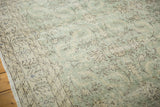 Distressed Oushak carpet section showing soft green and ivory tones with faded floral patterns.