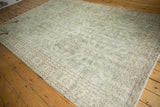 Distressed soft green Oushak border featuring curvilinear floral and leaf motifs.