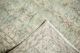 Distressed Oushak carpet with soft green and ivory colors, revealing hand-knotted back.