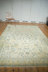 Distressed Sivas carpet border details, faded saffron field, celadon, navy floral motifs.