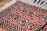 Blush field of a Vintage Bokhara rug, featuring intricate elephant footprint guls.