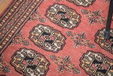 Blush vintage Bokhara rug with ivory, black, beige guls and patterned border.