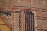 Folded corner of vintage Turkish Jijim rug showing hand woven texture, striped back, and fringe.
