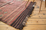 End view of vintage Jijim rug with horizontal red and charcoal stripes and fringe.