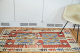 Vintage Turkish Kilim rug's upper geometric arrow border and abrashed red field.