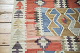 Geometric diamonds in abrashed red, blush, and denim blue on a vintage flatweave kilim rug.