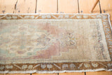 Mauve, celadon and ivory medallion pattern on a distressed Oushak rug mat.