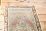 Hand-knotted distressed Oushak rug corner, revealing faded mauve, celadon, and bronze tones.