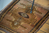 Oushak rug's bronze coffee medallion, germinating plant motifs, and dusty rose abrash.