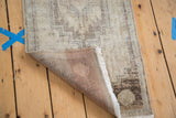 Vintage Oushak rug mat folded, showing neutral textured pile, white fringe, and hand-woven foundation.