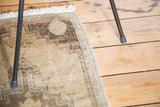 Textured hand knotted vintage Oushak rug corner with neutral beige pile and faded charcoal pattern.