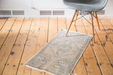 Distressed vintage Oushak rug with faded grey-beige stepped diamond medallion on sandalwood field.
