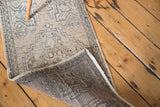 Distressed vintage Oushak rug corner with geometric patterns and dark hand-knotted foundation.