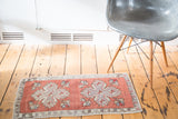 Distressed hand-knotted Oushak rug edge with faded brick red and beige floral motifs.