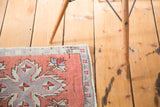 Distressed brick red and silver quatrefoil motifs on a vintage Oushak rug corner.