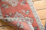 Distressed hand-knotted Oushak rug with faded brick red pile and floral details.