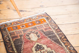 Oushak rug detail: expressive medallion with stepped edges, faded wine red, tangerine, and beige.