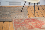 Fringed end of vintage Oushak rug mat, with terra cotta and faded tangerine patterns.