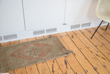 Vintage Oushak rug with muted beige field, burnt orange geometric pattern, and short fringe.