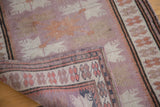 Folded vintage Oushak rug reveals hand-knotted pile, mauve floral guls, and intricate border.