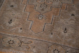 Oushak rug corner detail, highlighting simplistic tribal motifs, fringed edge, apricot and gray tones.