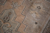 Close-up of the vintage Oushak rug pile with tribal geometric motifs in apricot and silver.