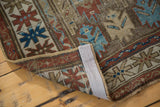 Hand knotted antique Caucasian rug corner, showing geometric red, blue patterns and sturdy selvedge.