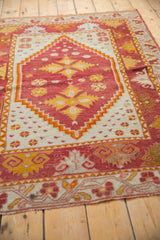 Vintage Oushak rug's hand-knotted corner, featuring cherry red, saffron, tangerine dragon border.