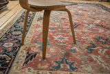 Blush red field of the vintage Heriz rug with serrated leaf and floral patterns.