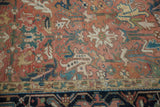 Blanched vintage Heriz rug: faded red field with ivory, teal serrated leaves, and dark blue border.