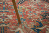 Blanched vintage Heriz carpet detail, showing faded cinnabar red, teal, and gold motifs.