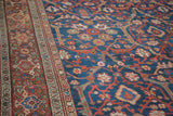 Close-up of antique Persian Mahal rug's indigo field and rust border with traditional floral motifs.