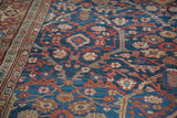 Antique Persian Mahal carpet with deep indigo field, sprawling rust and green floral motifs, patterned border.