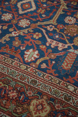 Intricate curvilinear rust floral motifs on the deep indigo antique Mahal carpet, showing a patterned border.