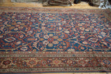 Sprawling indigo and rust curvilinear motifs on an antique Mahal carpet with a geometric border.