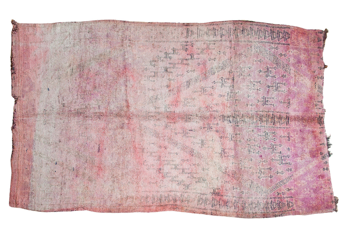 Vintage Moroccan carpet in overdyed cranberry, violet, faded geometric pattern, tattered ends.
